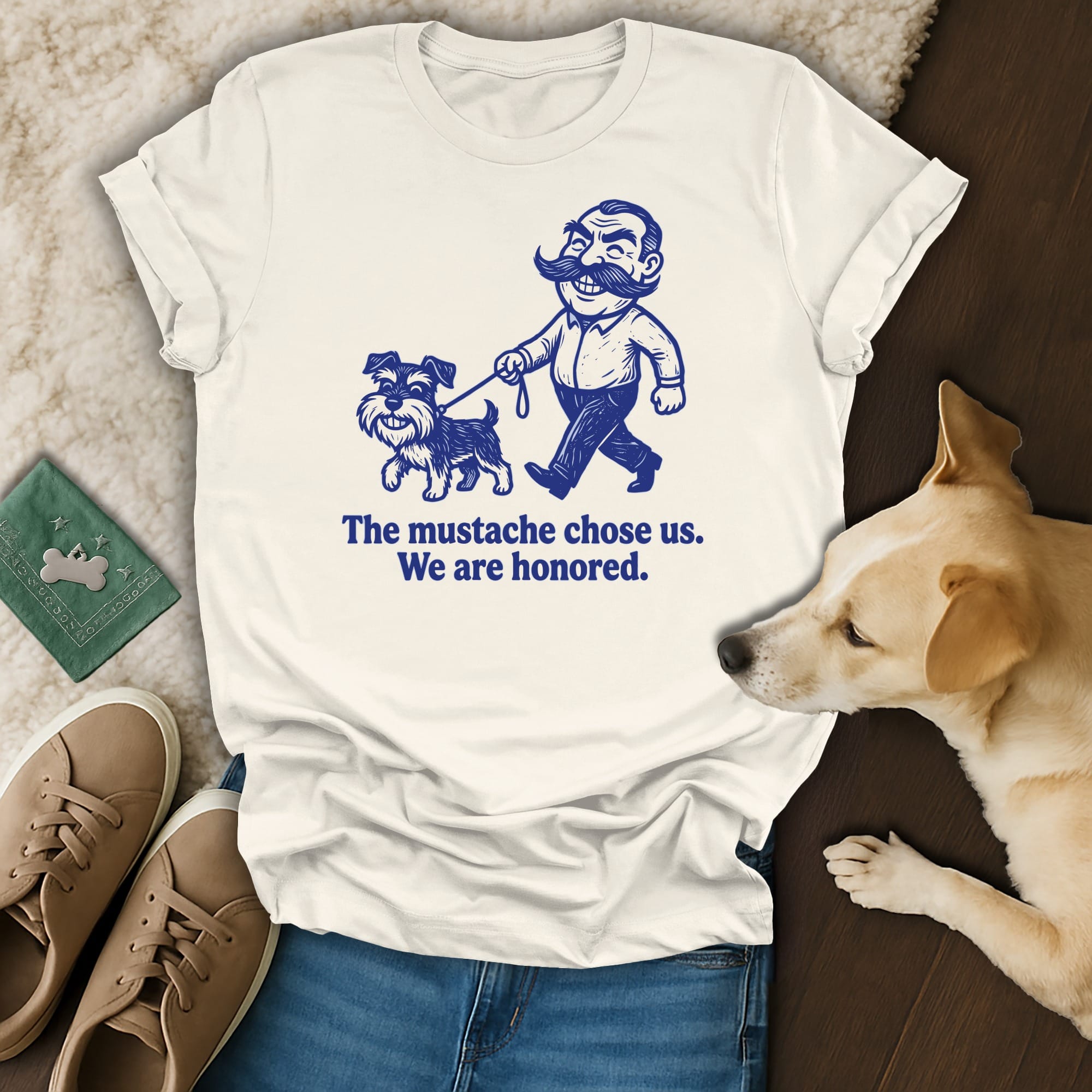 Cream t-shirt with a cartoon man and dog saying "The mustache chose us. We are honored."
