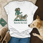 White t-shirt with illustration of woman and dog, "Born for the trail." text.