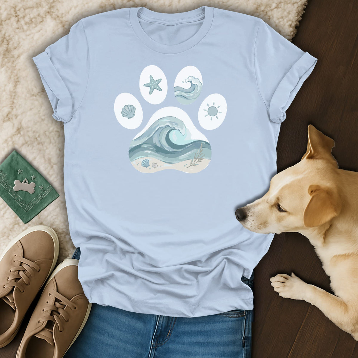 Light blue t-shirt with a paw print containing beach and wave illustrations.