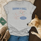 Light gray t-shirt with a line drawing of a dog playing with balls and text.