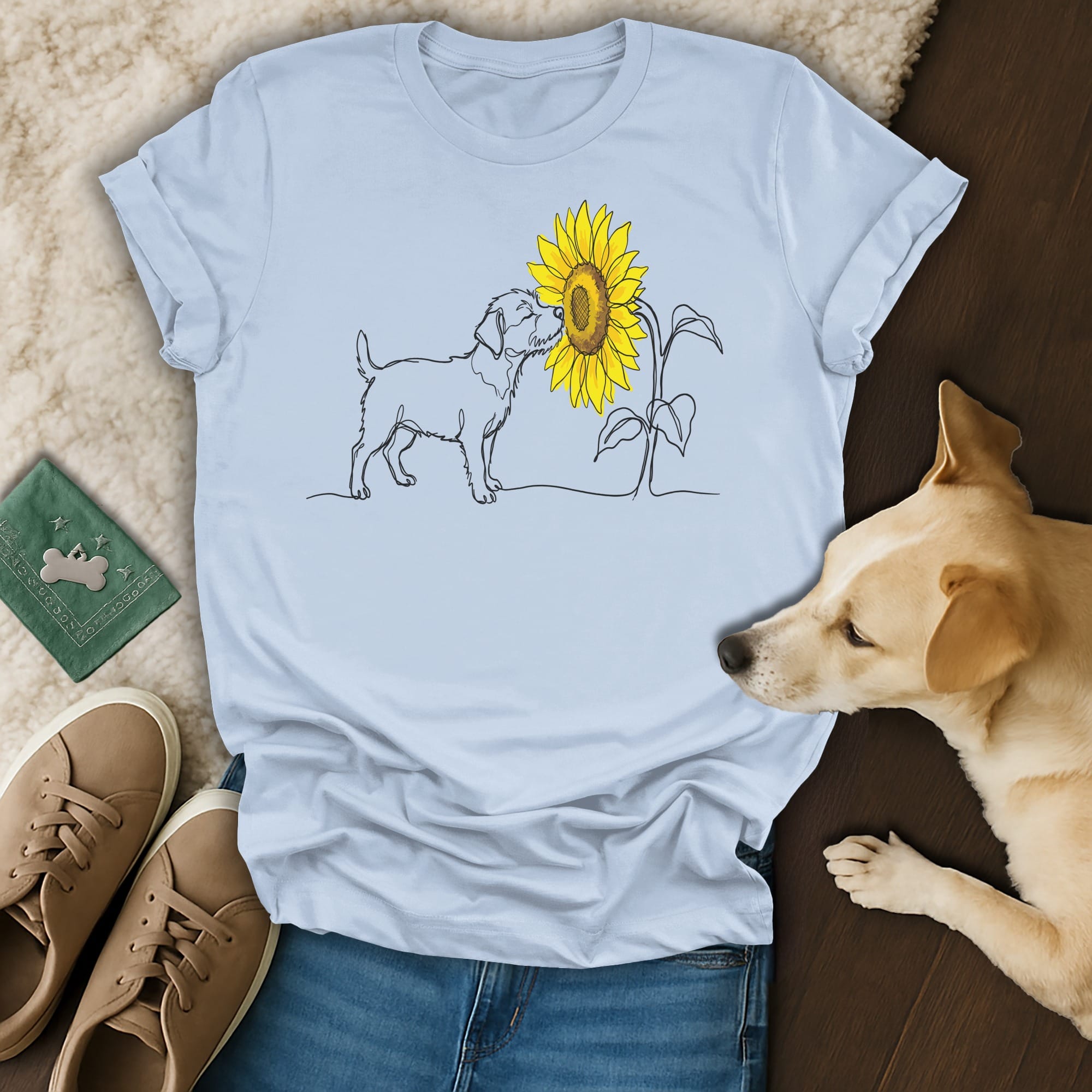 Line art of a dog sniffing a sunflower on a light blue t-shirt.