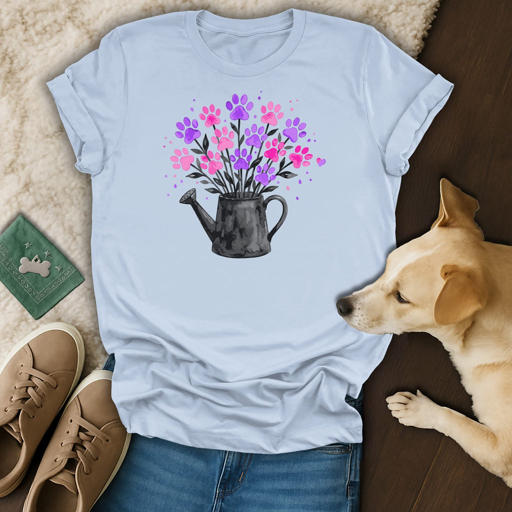 Light blue t-shirt with pink and purple paw print flowers in a watering can.