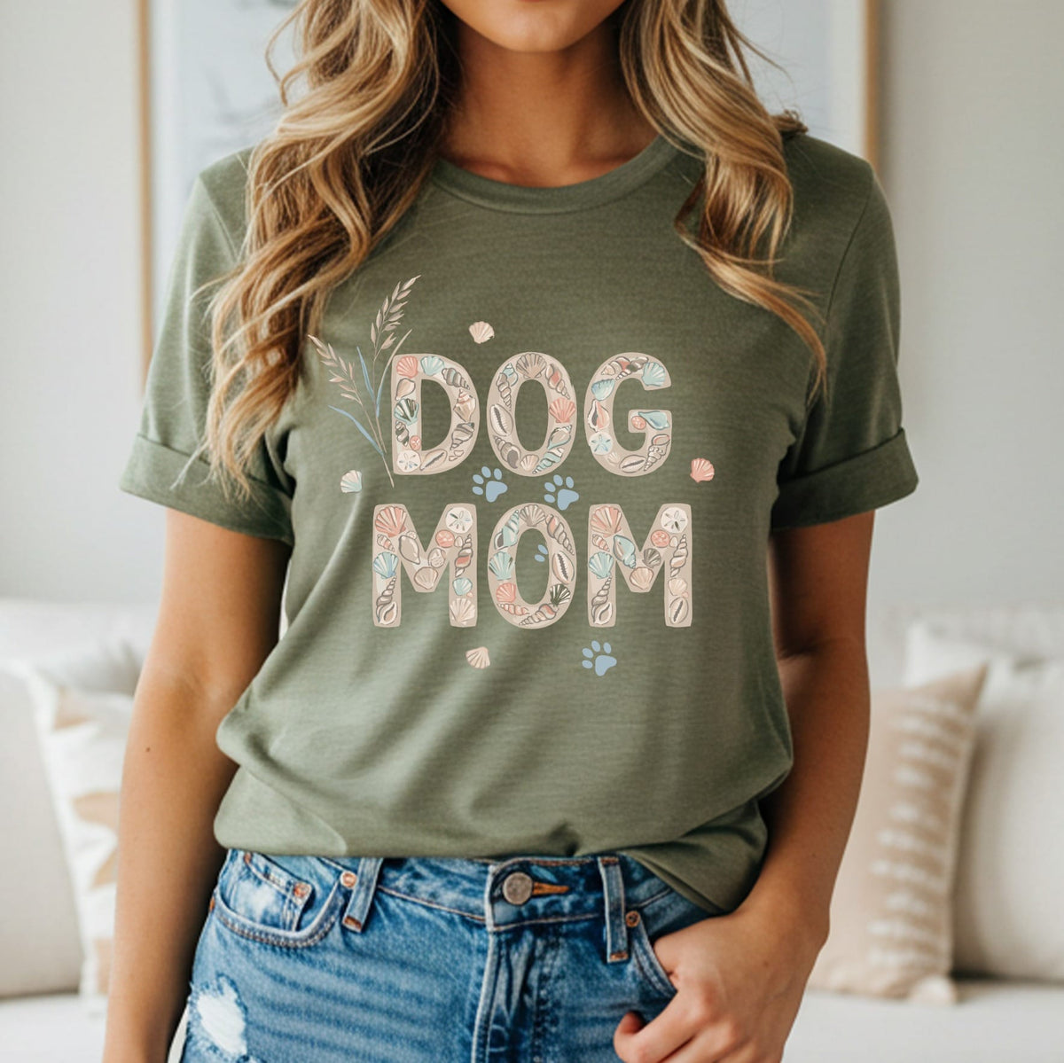 Olive green t-shirt with "DOG MOM" text made of shells and paw prints.