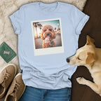 Light blue t-shirt with polaroid of dog wearing heart sunglasses eating ice cream.