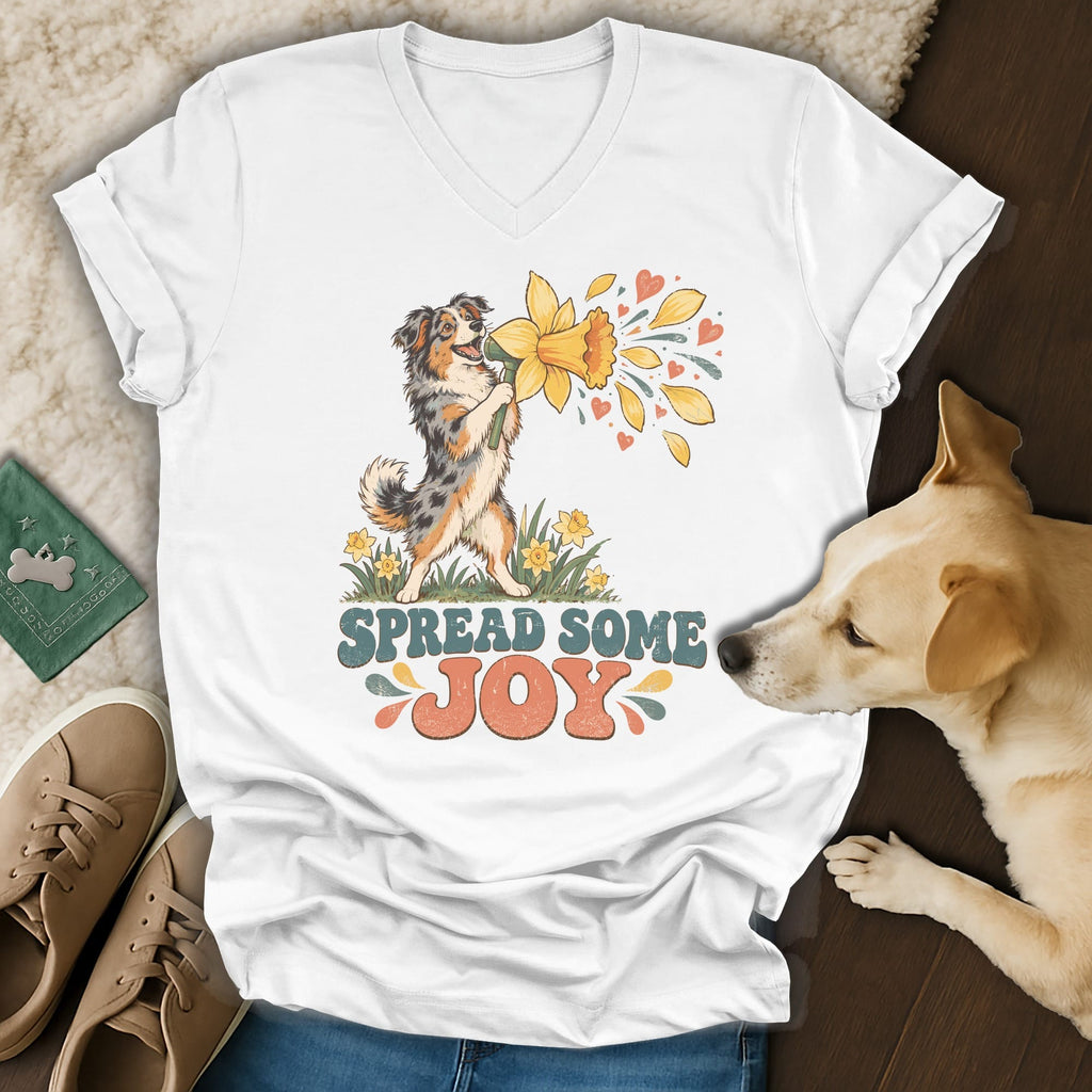 White V-neck t-shirt featuring a vintage-style graphic of an Australian Shepherd holding a daffodil with text reading SPREAD SOME JOY.