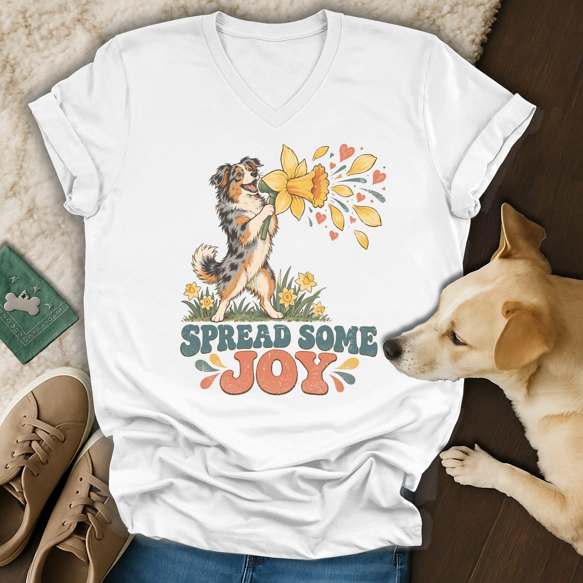 White V-neck t-shirt featuring a vintage-style graphic of an Australian Shepherd holding a daffodil with text reading SPREAD SOME JOY.