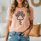 Peach t-shirt with a paw print design and small paw prints trailing down.