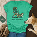 Green t-shirt with illustration of woman and husky, text "Born for the trail."