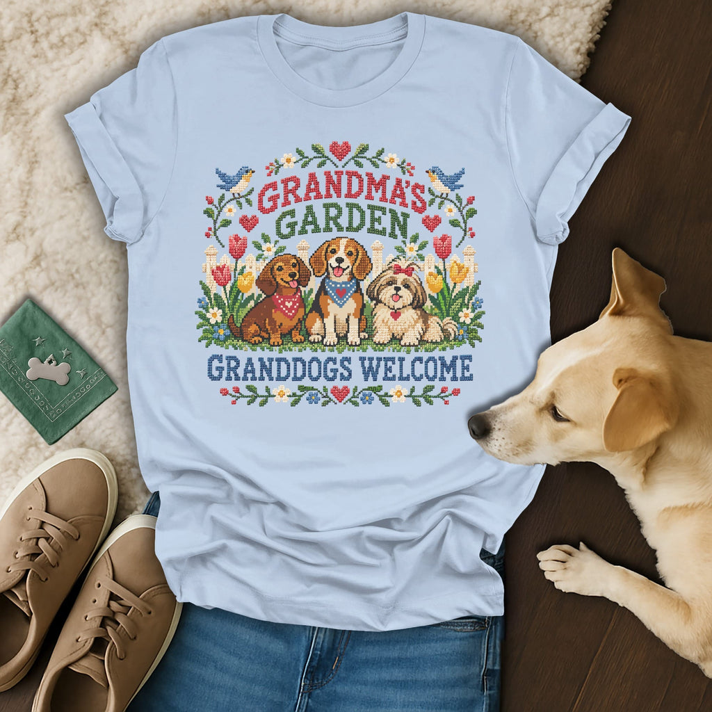 Light blue t-shirt featuring a cross-stitch design of three dogs and the text Grandma's Garden Granddogs Welcome.