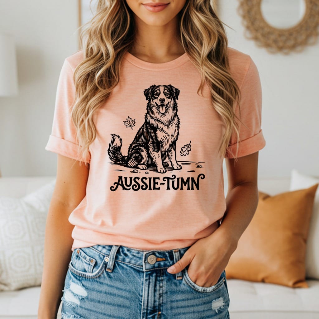 Black and white drawing of an Australian Shepherd on a peach t-shirt with "Aussie-Tumn" text.