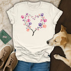 Cream t-shirt with a heart made of branches and colorful paw prints.