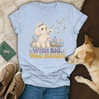 Light blue t-shirt featuring a cartoon dog, flowers, and the text Wish Big, Wag Bigger.