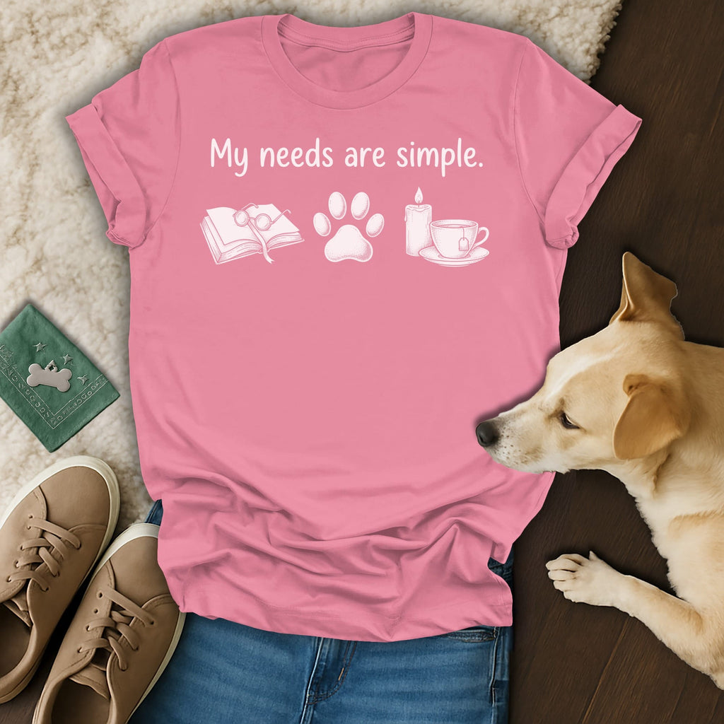 Pink t-shirt with "My needs are simple" and icons for book, paw print, candle, and tea.