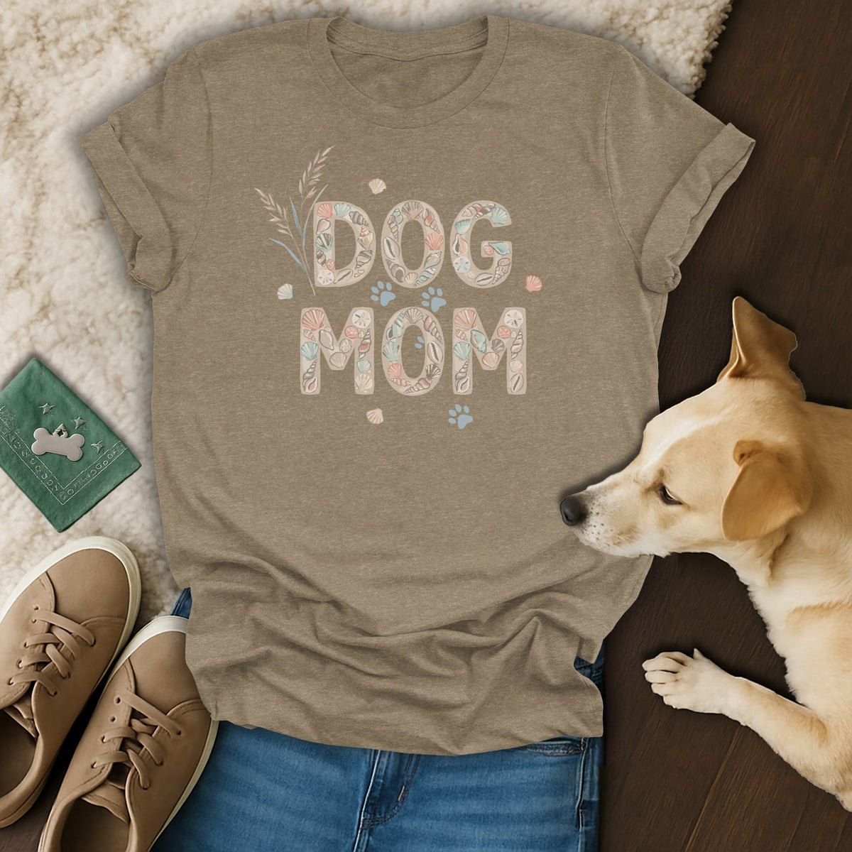 Tan t-shirt with "DOG MOM" text designed with shells and paw prints.