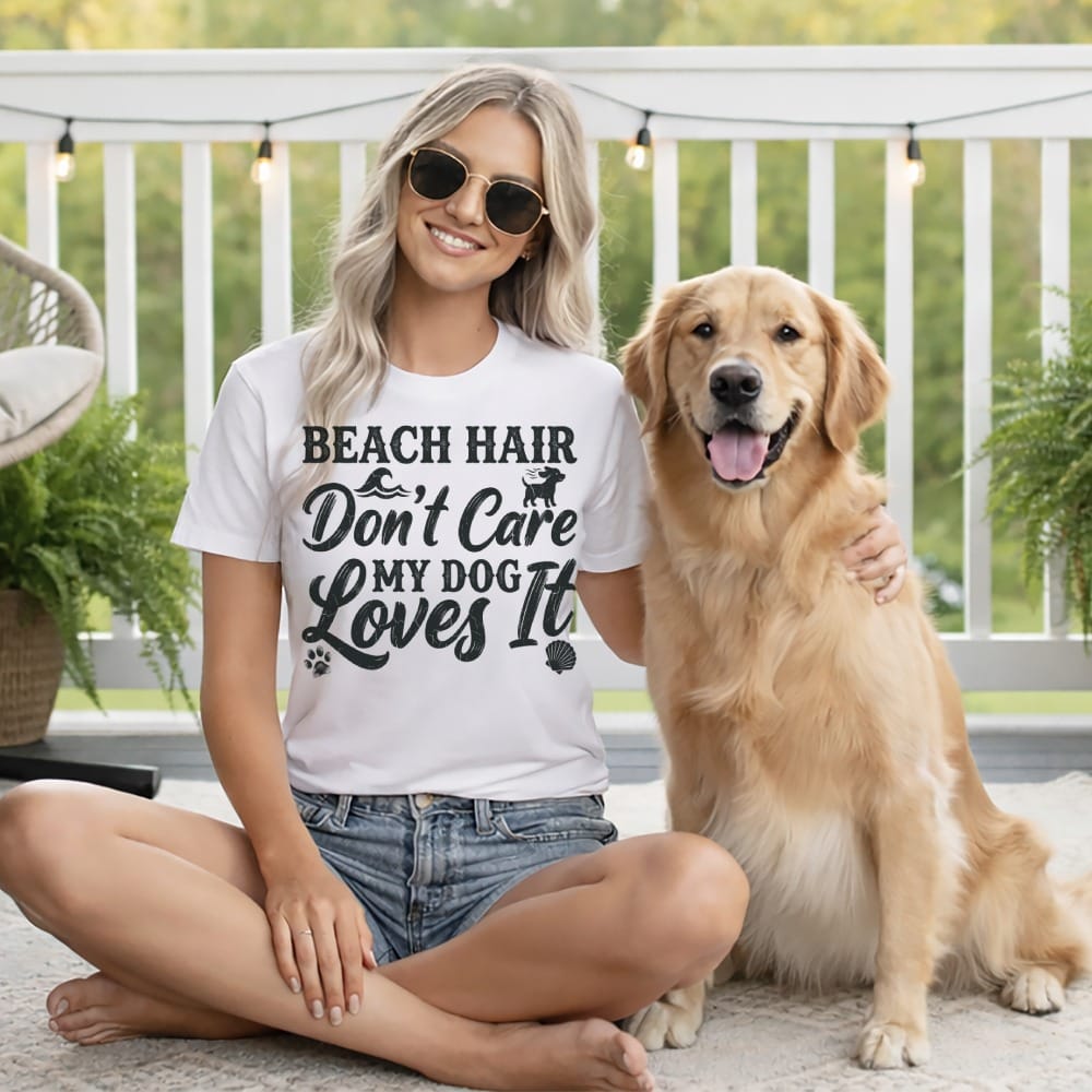 Woman in a white t-shirt with "Beach Hair Don't Care My Dog Loves It" text, sits with golden retriever.