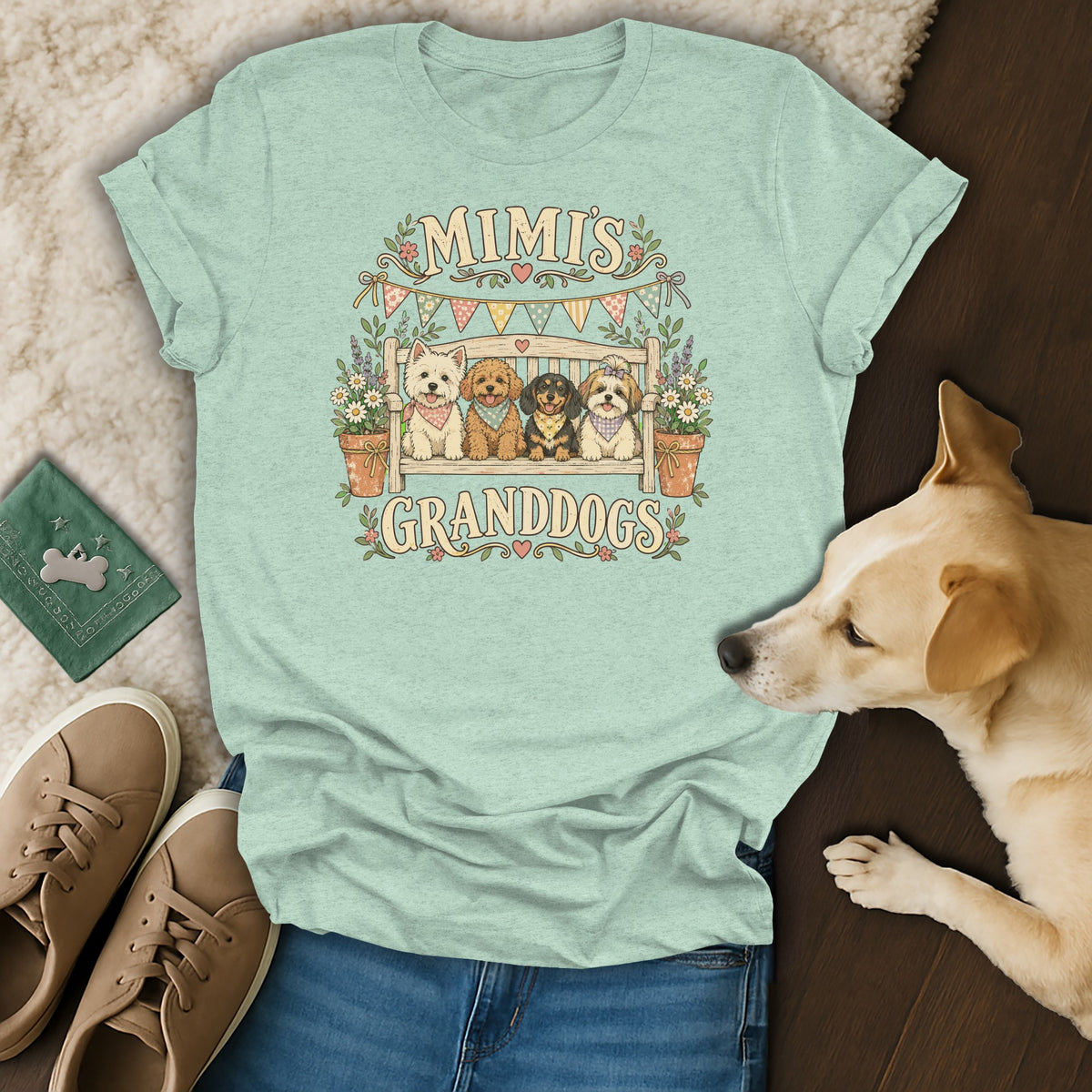 A light green t-shirt with a graphic of four dogs on a bench and the text MIMI'S GRANDDOGS.