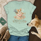 A light green t-shirt features a graphic of a corgi inside a teacup with the text Steeped in Love.