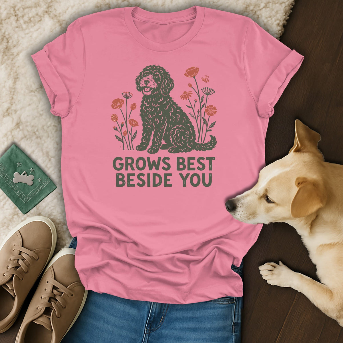 Pink t-shirt with a graphic of a curly dog, flowers, and the text GROWS BEST BESIDE YOU.