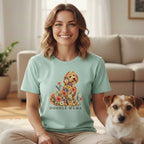 A smiling woman wearing a mint-green t-shirt with a floral doodle dog graphic and text reading DOODLE MAMA.