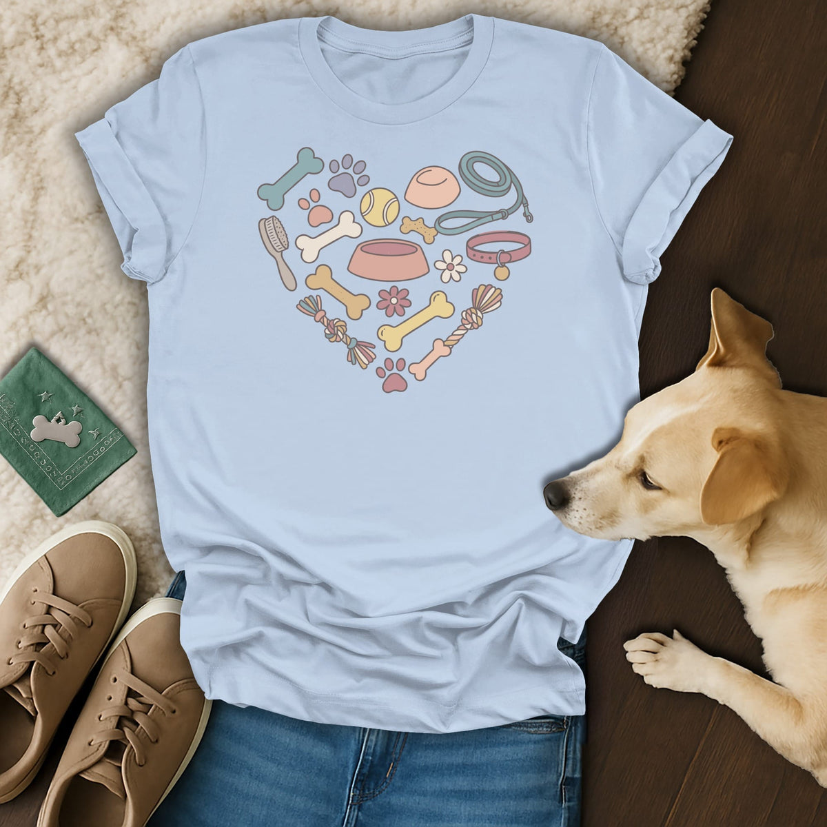 Light blue t-shirt with heart-shaped dog accessories and a tan dog lying beside it.
