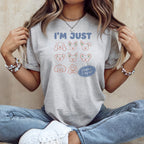 Light grey t-shirt with "I'M JUST" and dog faces, reading "playing it by ear".