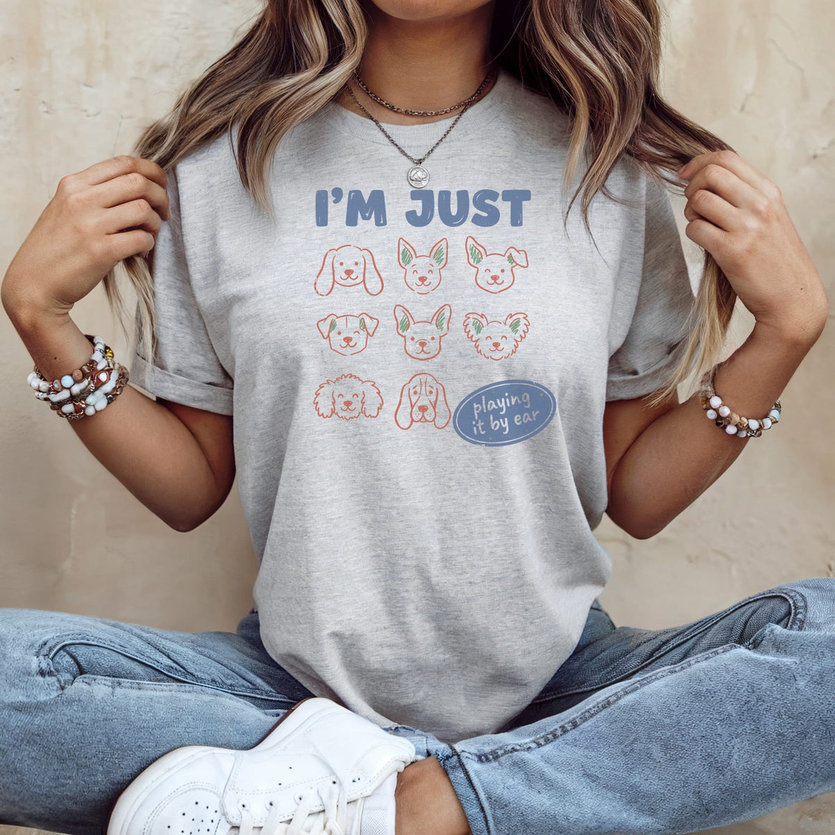 Light grey t-shirt with "I'M JUST" and dog faces, reading "playing it by ear".