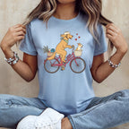 Illustration of dogs riding a bicycle with a basket of items and red hearts.