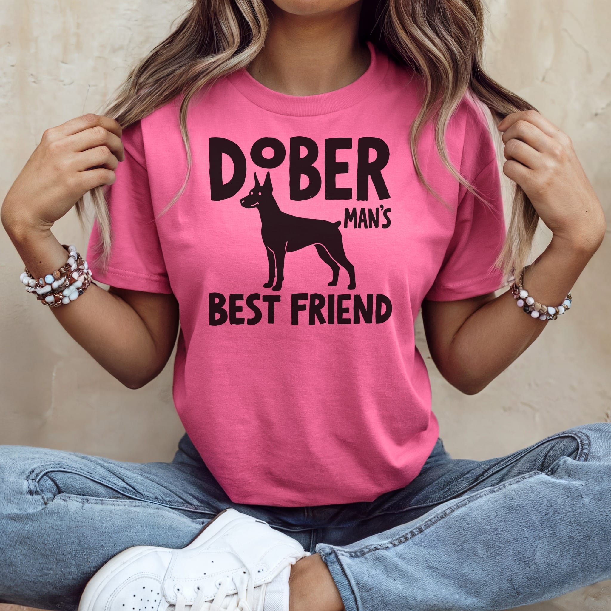 Woman wearing pink t-shirt with Doberman Pinscher graphic and "MAN'S BEST FRIEND" text.