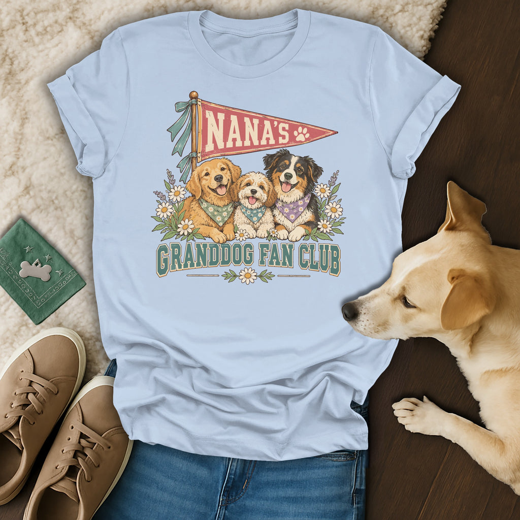 Light blue t-shirt featuring a Nana's Granddog Fan Club graphic with three dogs, surrounded by flowers, laid flat on a rug.