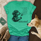 Green t-shirt with dachshund blowing dandelion seeds with paw prints.