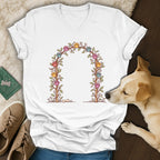 A white v-neck t-shirt displays an illustrated floral arch with colorful paw prints.