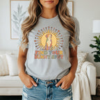 A woman wearing a gray t-shirt featuring a retro graphic of a dog and the text "Find Your Sunny Spot."