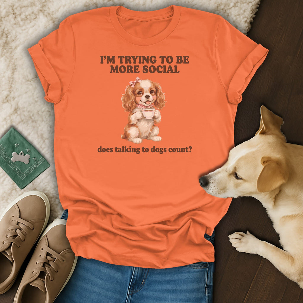 Orange t-shirt with a cartoon dog holding a teacup and text "I'm trying to be more social".