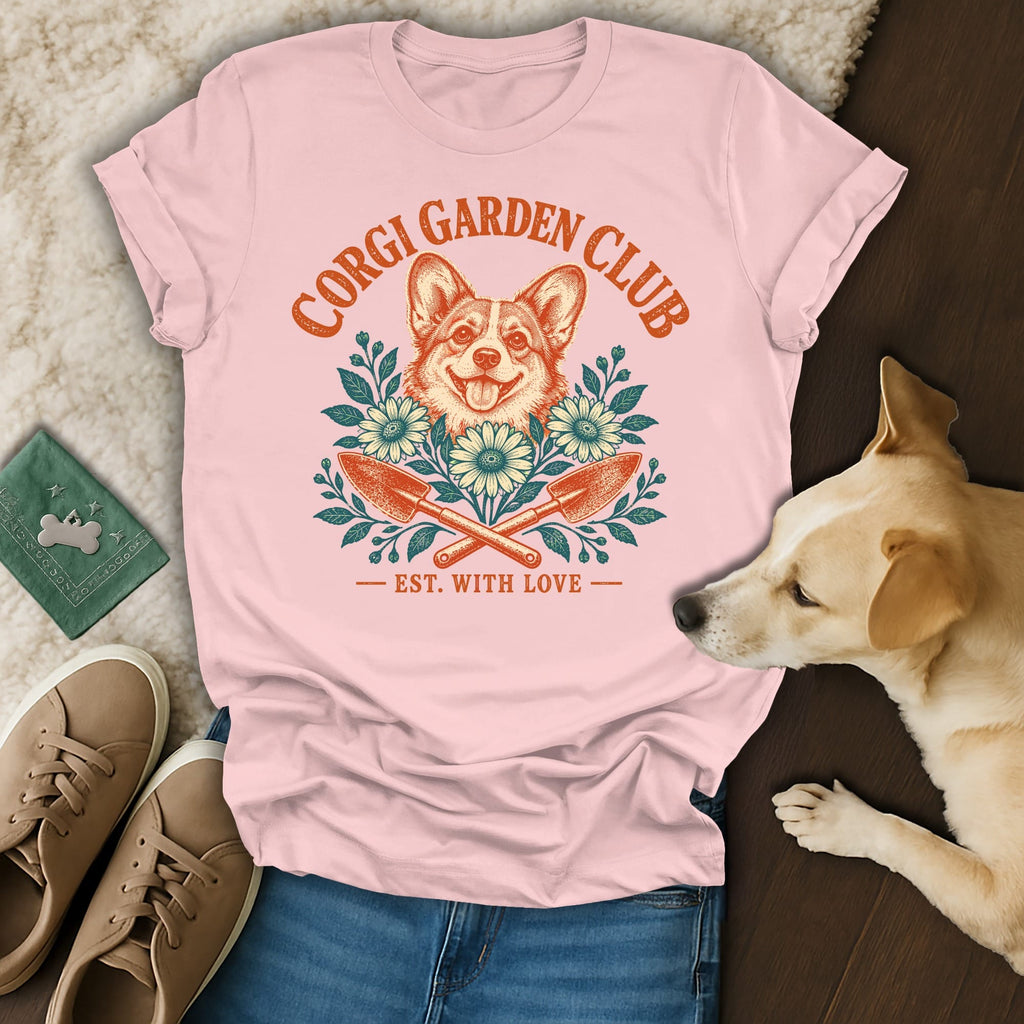 Pink t-shirt with a Corgi Garden Club graphic surrounded by flowers and garden tools, with a real dog, shoes, and jeans.