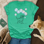Dog holding a bubble wand and blowing bubbles, on a teal t-shirt.