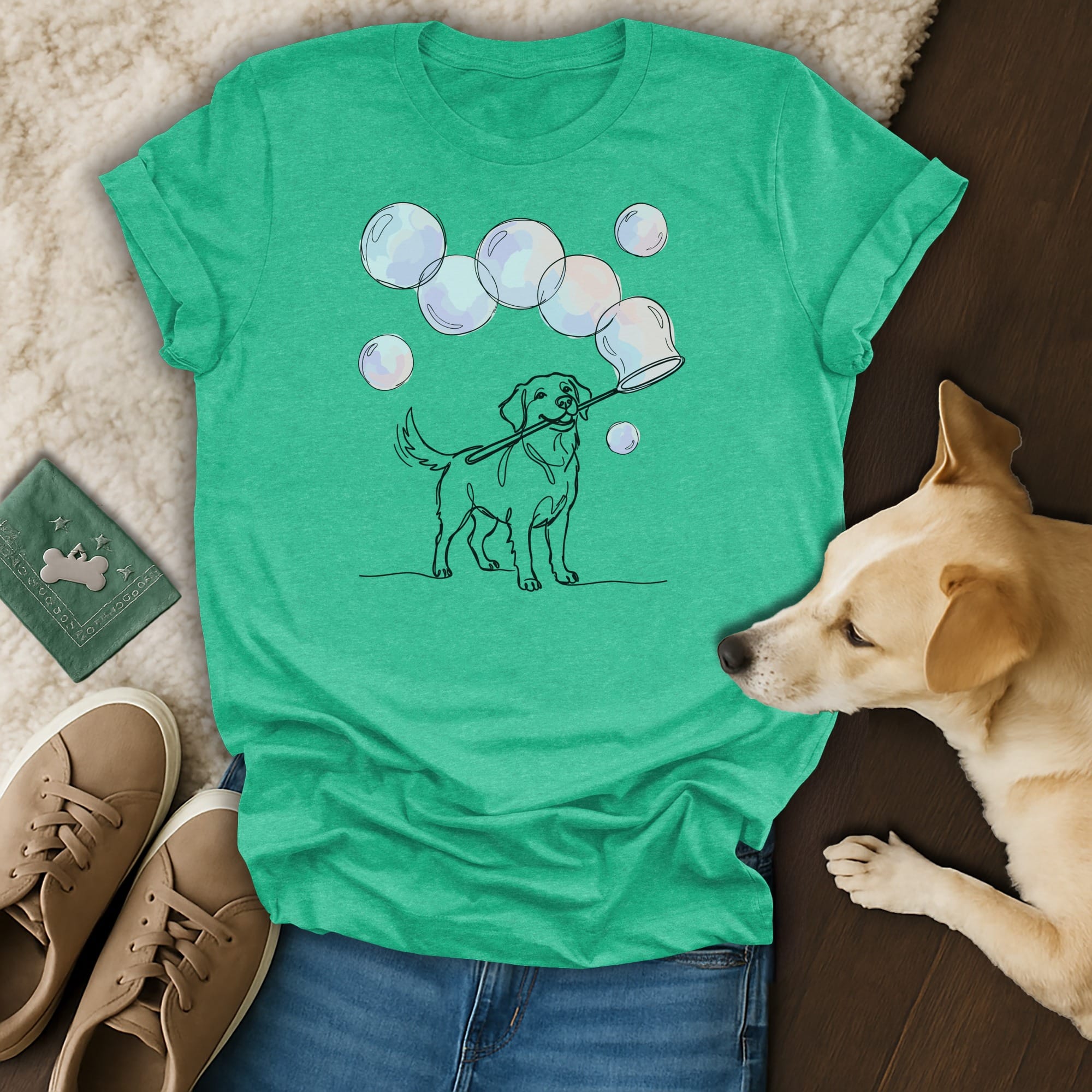 Dog holding a bubble wand and blowing bubbles, on a teal t-shirt.