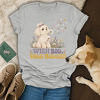 Heather gray t-shirt featuring a graphic of a puppy blowing dandelion seeds and the text Wish Big, Wag Bigger.