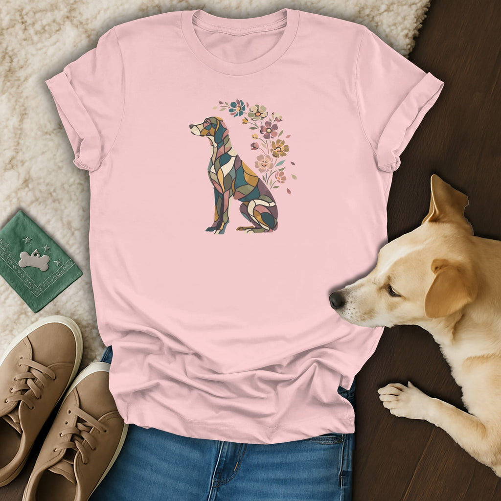 A pink t-shirt featuring a stained-glass style dog graphic with floral accents, laid out with blue jeans, tan shoes, and a real dog.