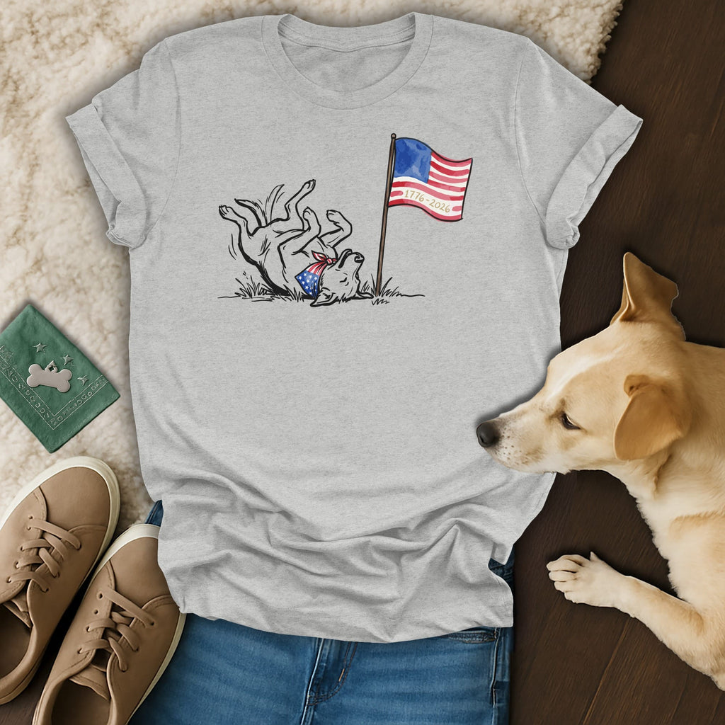 Dog wearing bandana rolls near American flag with 1776-2026 text.