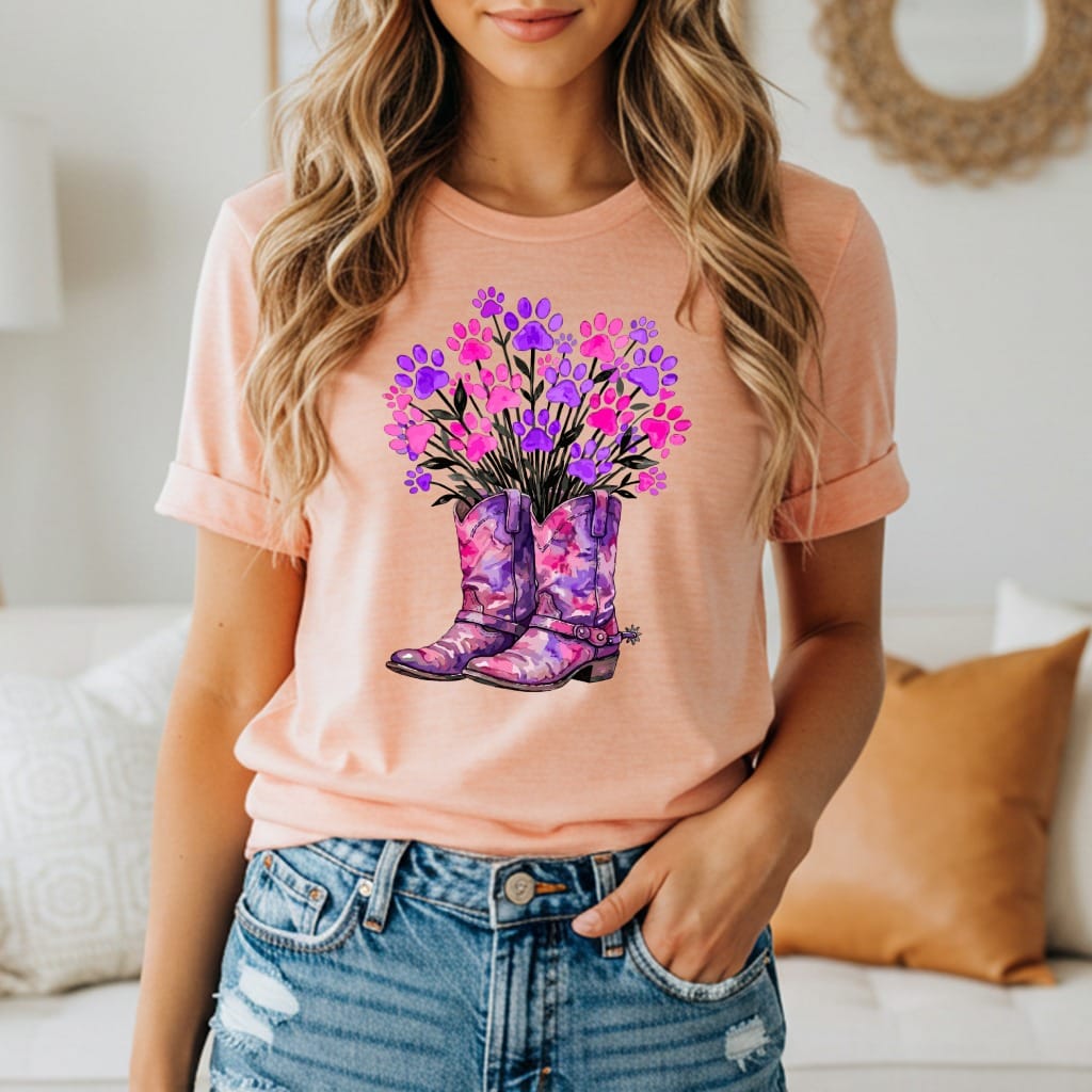 Peach t-shirt with purple cowboy boots and pink and purple paw print flowers.