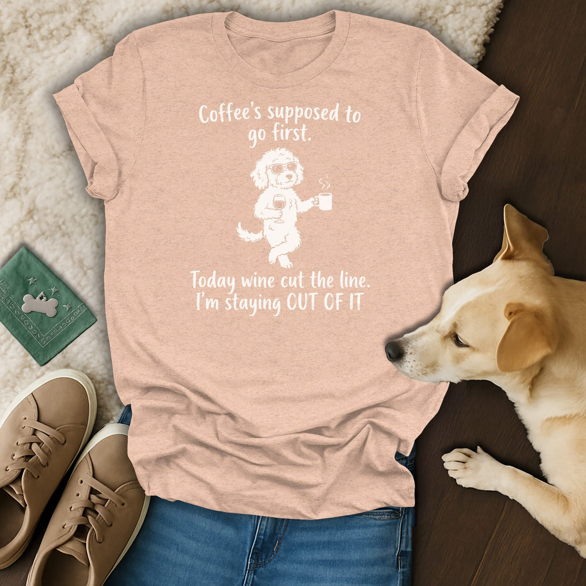 Peach t-shirt with white text: "Coffee's supposed to go first." and graphic of a dog holding wine and coffee.