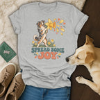 Grey t-shirt featuring an Australian Shepherd graphic, the text "Spread Some Joy," and surrounding lifestyle items.
