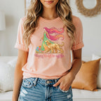 Woman in peach t-shirt with woman and dog graphic and "Flowing through life together" text.