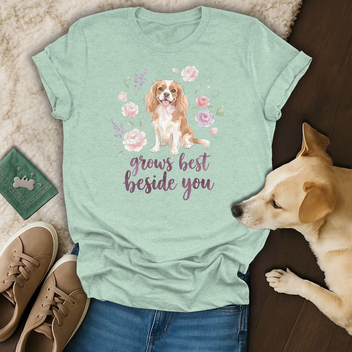 A mint green t-shirt with a Cavalier King Charles Spaniel graphic and the text grows best beside you.