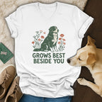 A white V-neck t-shirt featuring a green and red graphic of a Bernese Mountain Dog surrounded by flowers and the text GROWS BEST BESIDE YOU.